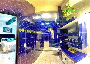 A bathroom with blue tiles, a toilet, a sink, and a shower area.