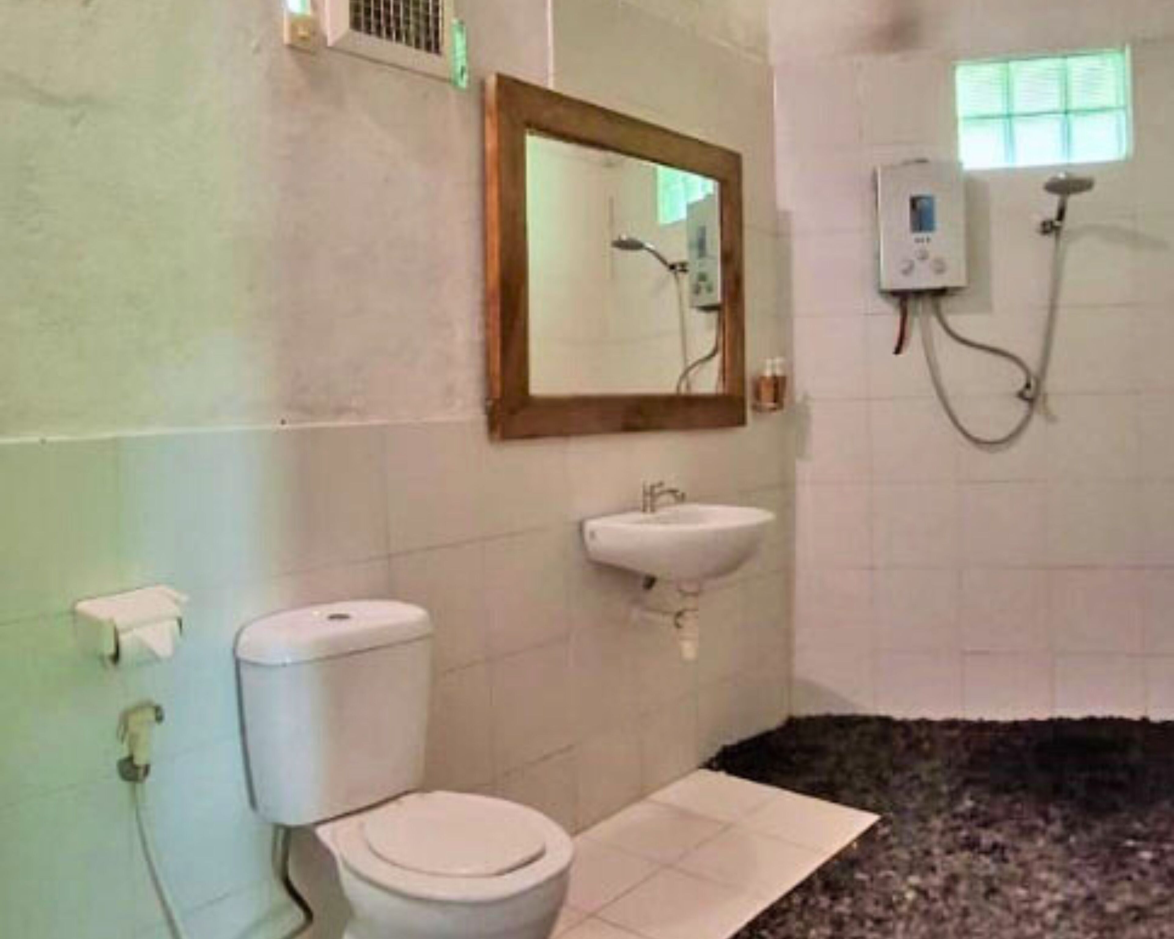 A bathroom with a toilet, sink, and a shower area.