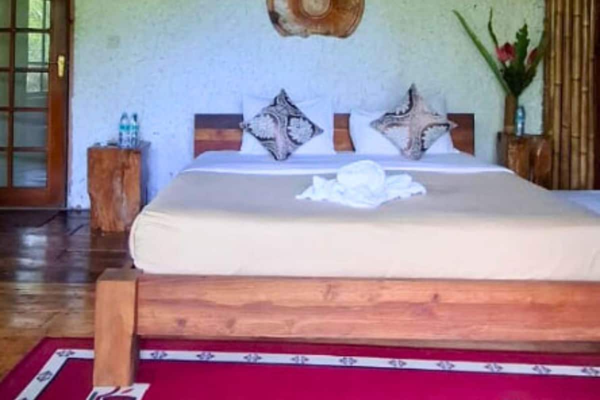 A bedroom with a wooden bed, a round wall decoration, and a small wooden nightstand with a vase.