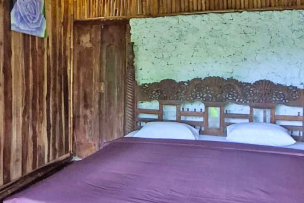 A room with a wooden headboard, a purple bedspread, and a green textured wall.