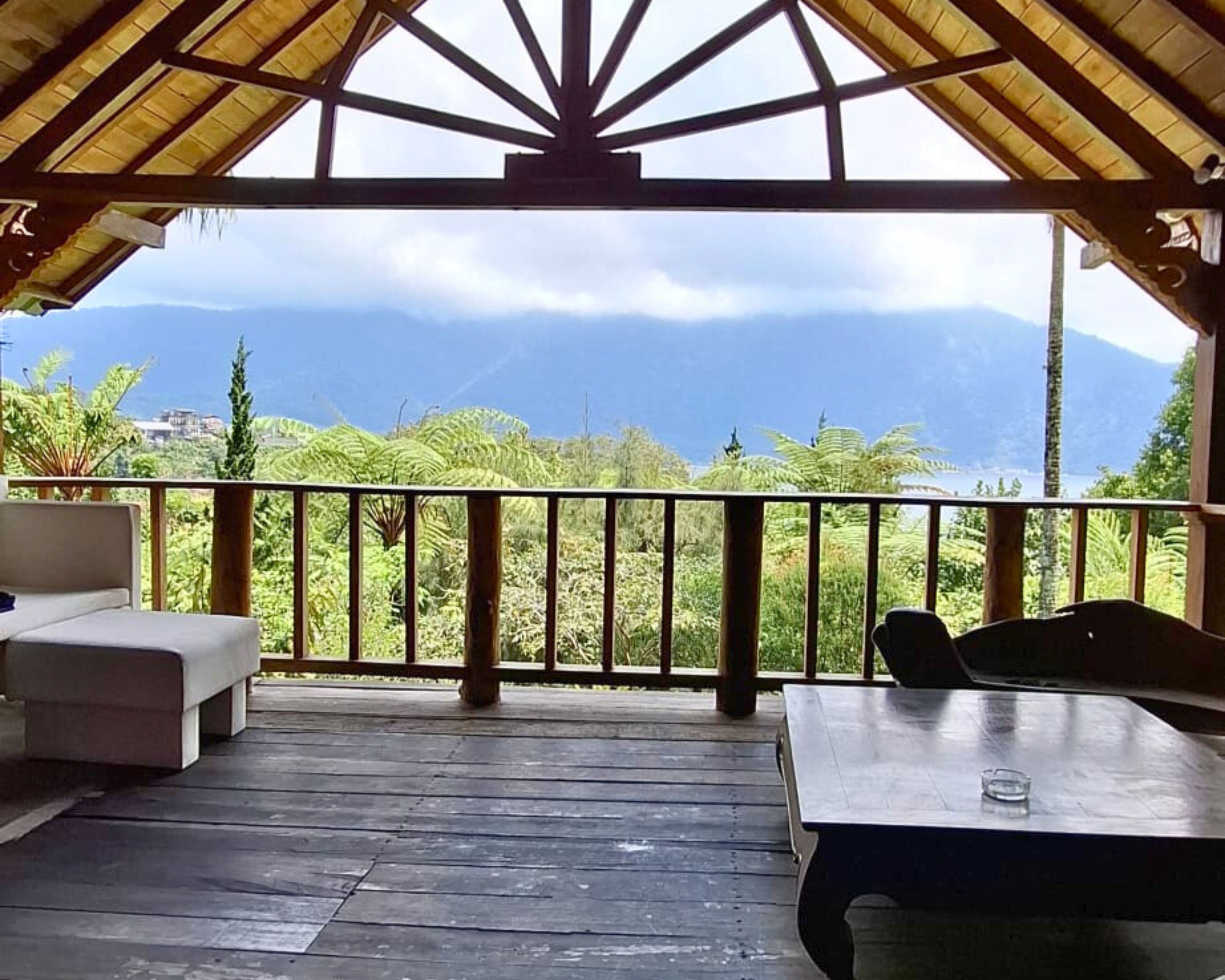 A covered outdoor seating area with a view of mountains and greenery.