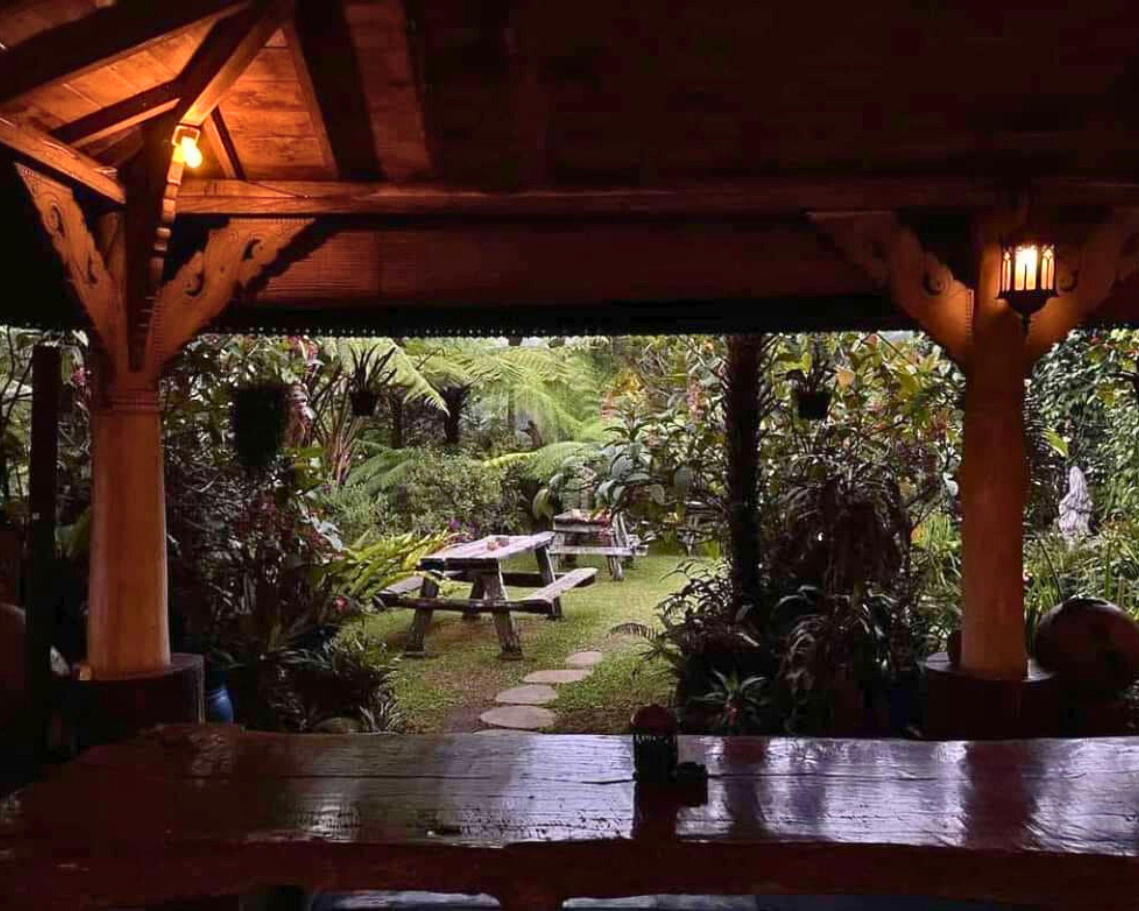 Un padiglione in legno all'aperto con un sentiero in pietra che conduce a un tavolo da picnic immerso nel verde.
