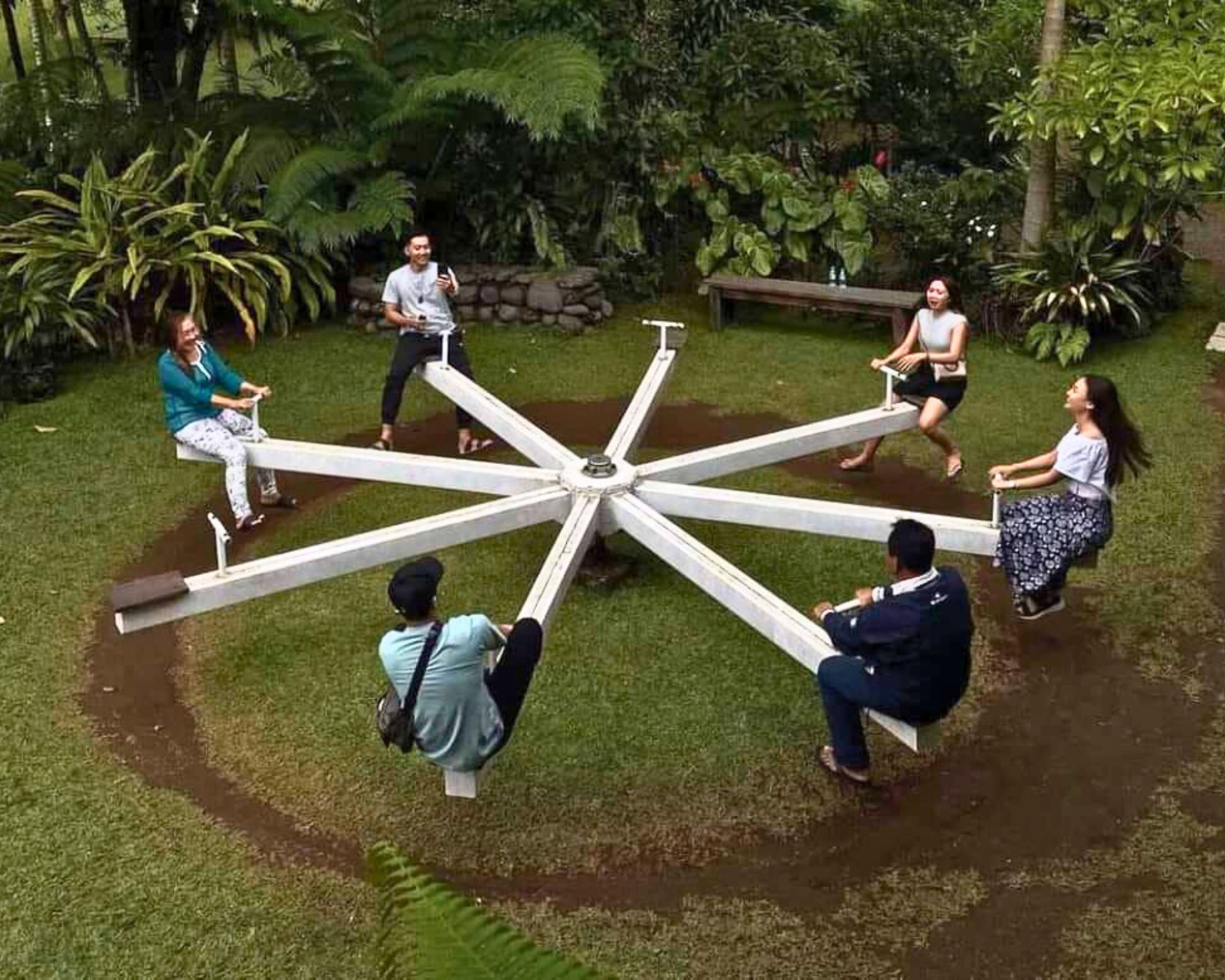 Un espacio de estar al aire libre con forma circular, una mesa central y bancos alrededor.