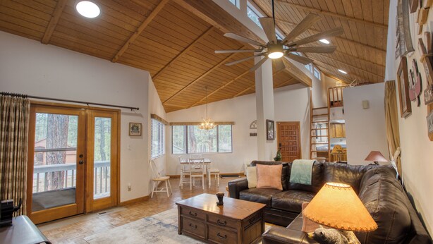 A spacious living room with a wooden ceiling, a leather sofa, a coffee table, and a ceiling fan. - Black Bear Retreat - Wonderful 3 bed cabin in Pinetop with a fenced yard & Wifi. (Pinetop)