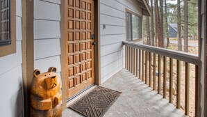 A wooden door with a grid pattern, a bear-shaped door knocker, and a wooden railing on a porch. - Black Bear Retreat - Wonderful 3 bed cabin in Pinetop with a fenced yard & Wifi. (Pinetop)
