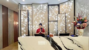 A reception desk with a marble top, a decorative wall with geometric patterns, and a vase with flowers. - d'primahotel PIK Jakarta (Jakarta)