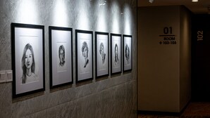 A hallway with framed portraits on the wall, a marble floor, and a sign indicating room numbers 101 and 102. - d'primahotel PIK Jakarta (Jakarta)
