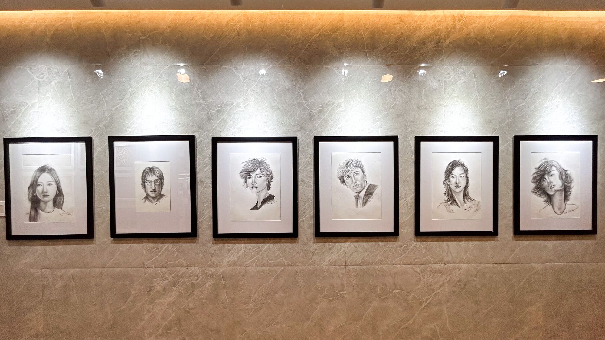 A series of framed portraits on a wall.