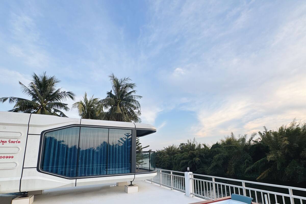 A modern boat with a glass-enclosed area and a hot tub on deck.