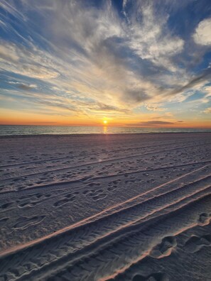 A beach with footprints leading towards the ocean at sunset. - PET FRIENDLY, Family Friendly condo with shared pool, tennis court. (Panama City Beach)
