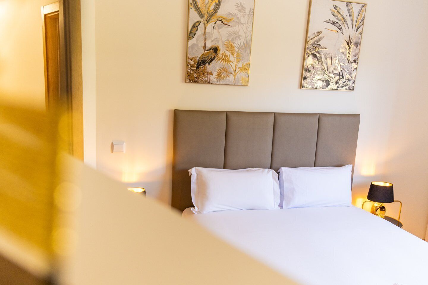 A hotel room with a large bed, two wall-mounted paintings, and bedside lamps.