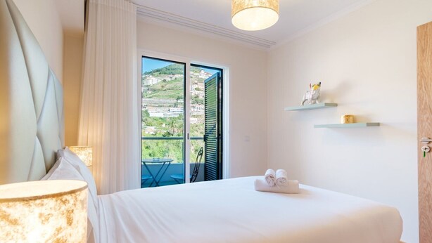 Un dormitorio con cama, ventana con vistas, lámpara y puerta.