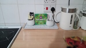 Un plan de travail de cuisine avec une machine à café, une boîte de chocolats Matchmakers et une bouilloire.