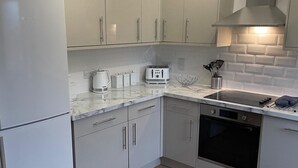 A modern kitchen with grey cabinets, a built-in oven, and a countertop with a kettle, toaster, and other appliances.