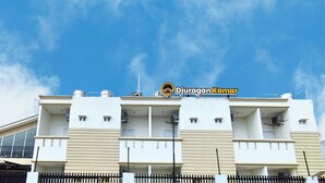 A modern building with a flat roof, multiple balconies, and a clear sky. - Djuragan Kamar Macan Kumbang (Palembang)