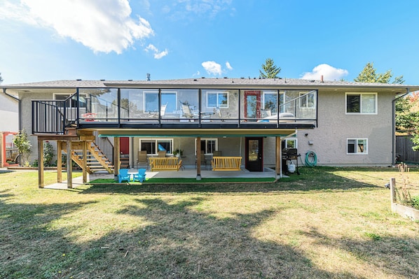 A two-story house with a covered patio, a wooden deck, and a visible staircase.