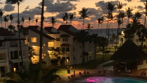 Un resort con piscina, palmeras y edificios con balcones.
