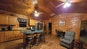A log cabin interior with a kitchen, dining area, and a bar.