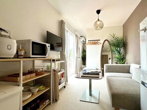 A compact living space with a kitchenette, a flat-screen TV, a dining table, and a sofa. - Solana Kujyukuri (Kujukuri)