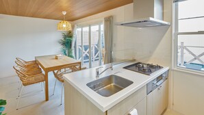 Una cucina moderna con isola centrale, una zona pranzo con sedie in vimini e un'ampia finestra con vista.