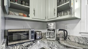 Eine Küche mit Mikrowelle, Toaster, Kaffeemaschine und Wasserkocher auf einer Granitarbeitsplatte.