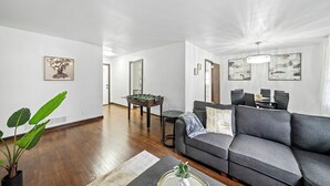 Ein modernes Wohnzimmer mit einem grauen Sofa, einem Kicker und einem Essbereich mit Tisch und Stühlen.