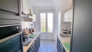 A modern kitchen with dark cabinetry, a central island, and a view to the outside.