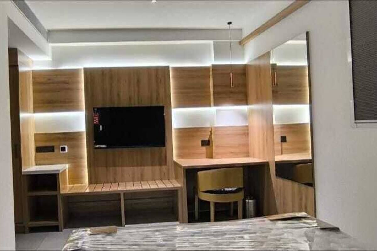 A modern room with a flat-screen TV mounted on the wall, wooden paneling, a bench, and a small table with chairs.