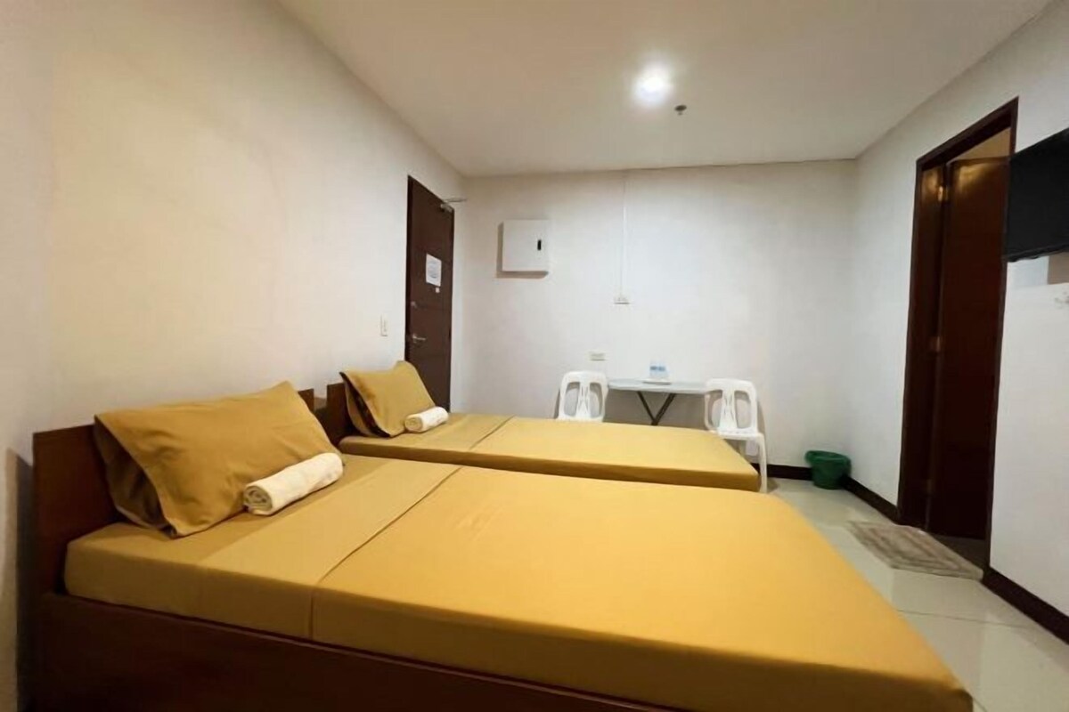 A room with two beds, a small table, and a chair.