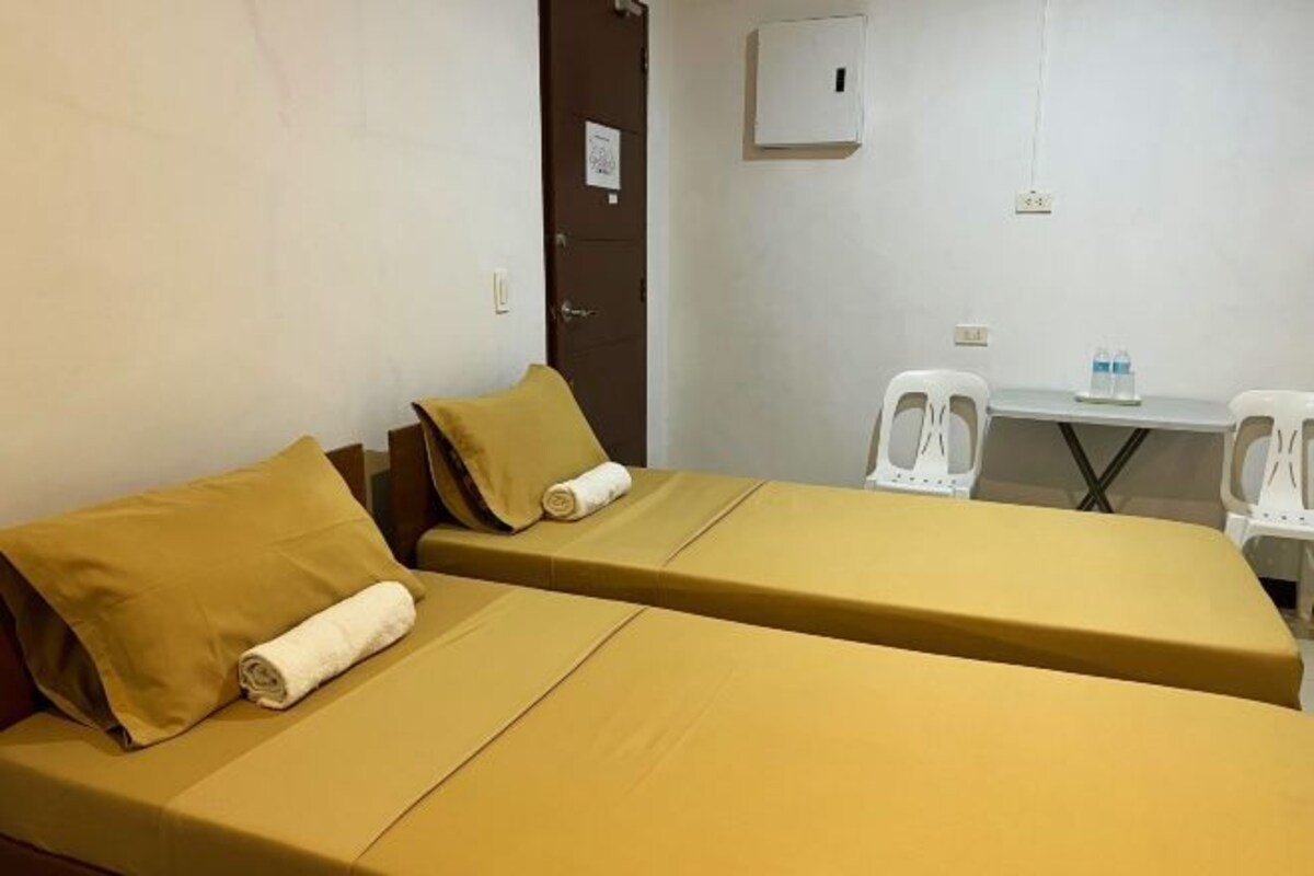 A hotel room with two beds, a small table, and two chairs.