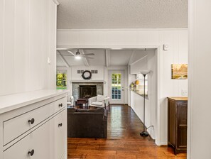 Un salón amplio con chimenea, ventilador de techo y vistas al exterior.