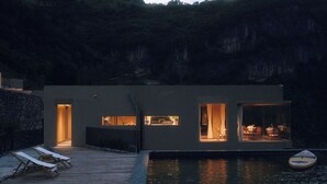 Ein modernes Haus mit Pool, einer Holzterrasse und Liegestühlen.