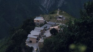Ein Hotel an einem Hang mit mehreren Gebäuden, darunter ein auffälliges Bauwerk mit Glasdach und ein kreisförmiges Steinhaus.