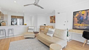 A modern living room with a sofa, a coffee table, and a TV mounted on the wall. - Chic Coastal Charm on Palm Beach (Palm Beach)