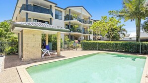 A residential building with a swimming pool, outdoor seating, and a covered patio area. - Chic Coastal Charm on Palm Beach (Palm Beach)