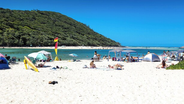 A beach with tents, umbrellas, and people relaxing. - Chic Coastal Charm on Palm Beach (Palm Beach)