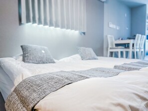 A hotel room with a bed, pillows, a bedside table, and a chair. - HANASTAY HITSUJI (Osaka)