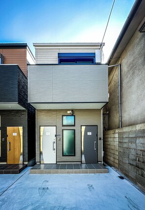 A modern building with a flat roof, a central entrance, and a small overhang above the doors. - HANASTAY HITSUJI (Osaka)
