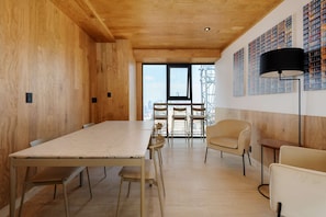 A modern interior with a wooden ceiling, a large table, and chairs, and a city view through large windows. - Casa Colón - Rooftop Relaxation with Monumental Views (Ciudad de México)