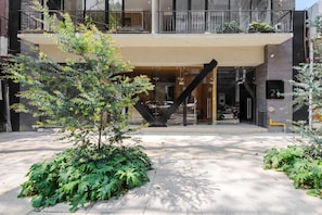 A modern building with a covered entrance, outdoor seating, and a staircase leading to an upper level.