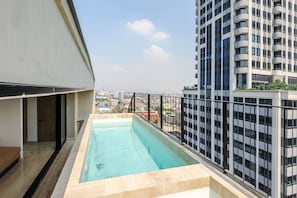 A rooftop swimming pool with a view of a cityscape and a tall building in the background.