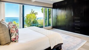 A bedroom with a large bed, a view of the ocean, and a black wardrobe. - Stylish Camps Bay Home with Sea Views Beleza Villa (Cape Town)