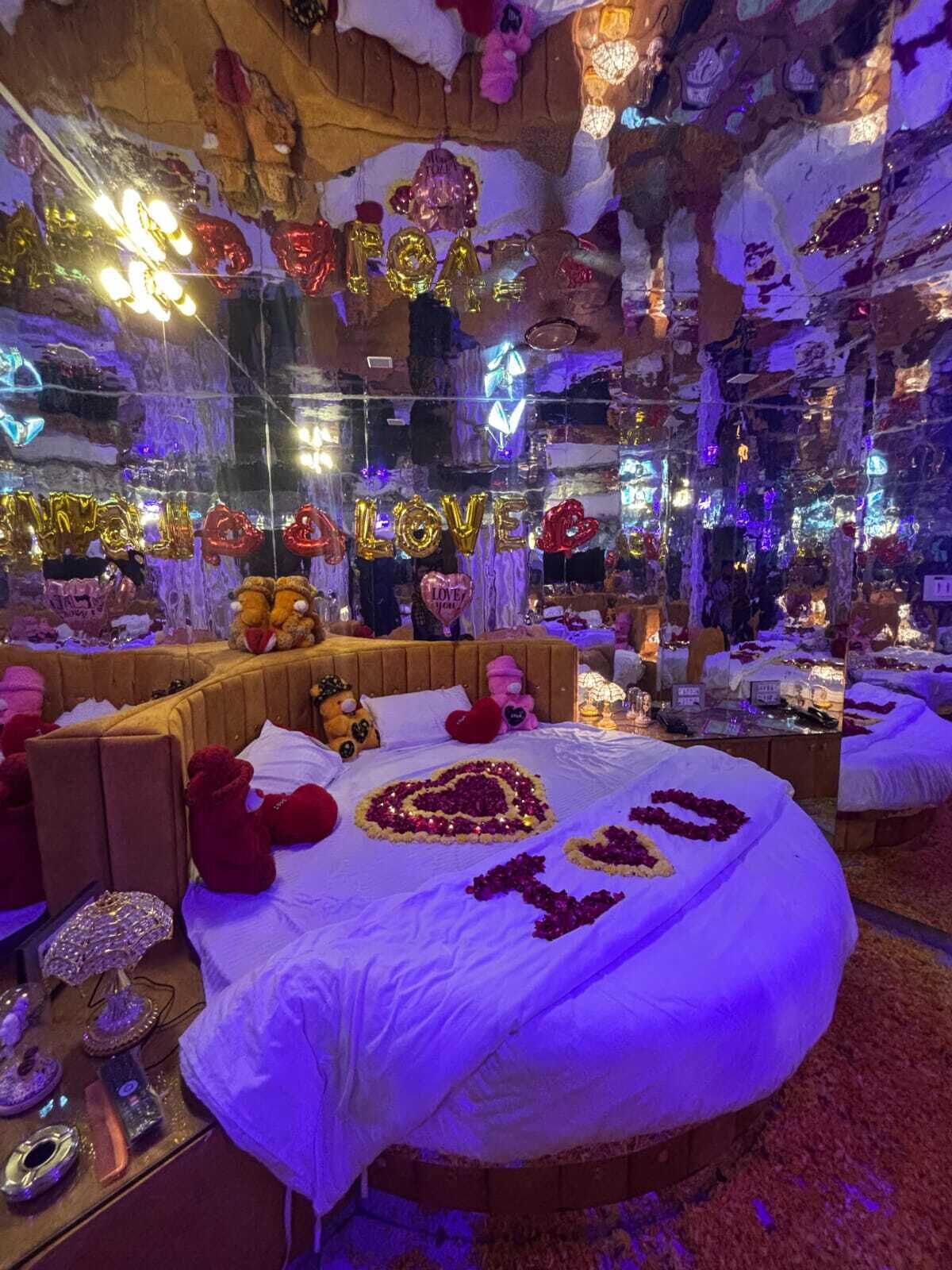 A circular bed with white bedding, surrounded by plush toys and heart-shaped decorations.