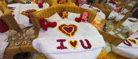 A room with a bed decorated with heart-shaped flower arrangements and the name "Ivu" on the pillow.