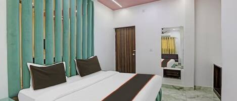 A hotel room with a bed, a ceiling fan, a door, and a mirror.