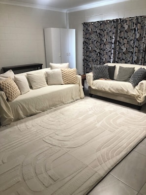 A living room with a sofa set, a patterned curtain, and a white wardrobe.