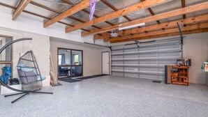 En rummelig garage med betongulv, en hængekøjsstol og et træskab.