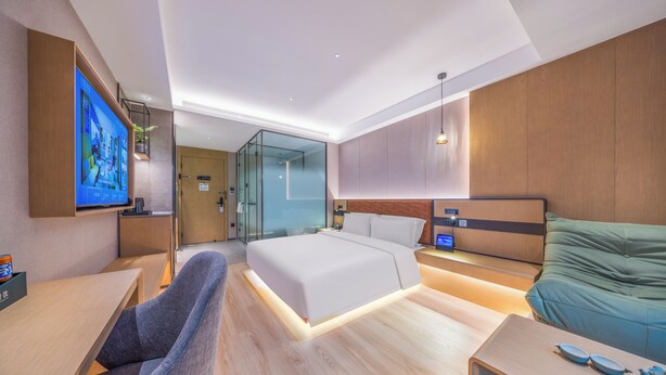 A modern hotel room with a large bed, a desk, a chair, a TV, and a glass partition separating the room from the hallway. - True Go S Hotel Nanshan Nantou (Shenzhen)