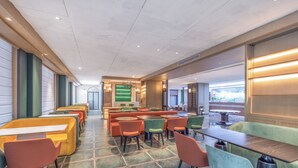 A spacious indoor seating area with multiple tables and chairs, a green accent wall, and a view through a large window. - True Go S Hotel Nanshan Nantou (Shenzhen)