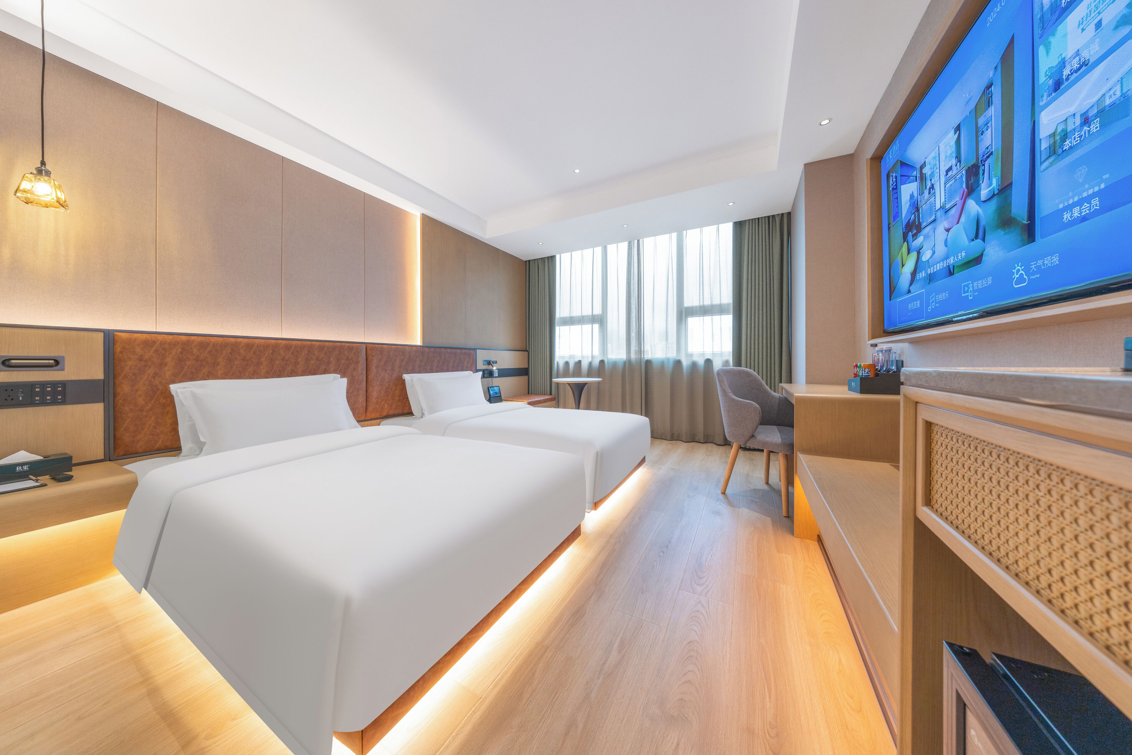 A hotel room with two beds, a TV, a desk, and a chair.
